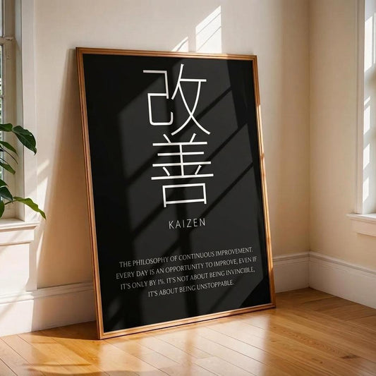 A framed vertical poster leaning against a beige wall on a wooden floor in a sunlit room. The poster has a black background with large white Chinese characters, the word 'KAIZEN' in Latin letters, and a short quote below.