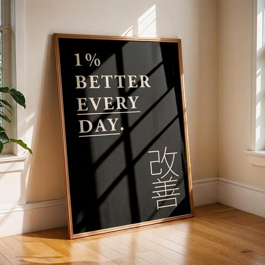 A framed motivational poster leaning against a beige wall in a sunlit room with wood floors. The poster has a black background with white text reading '1% BETTER EVERY DAY.