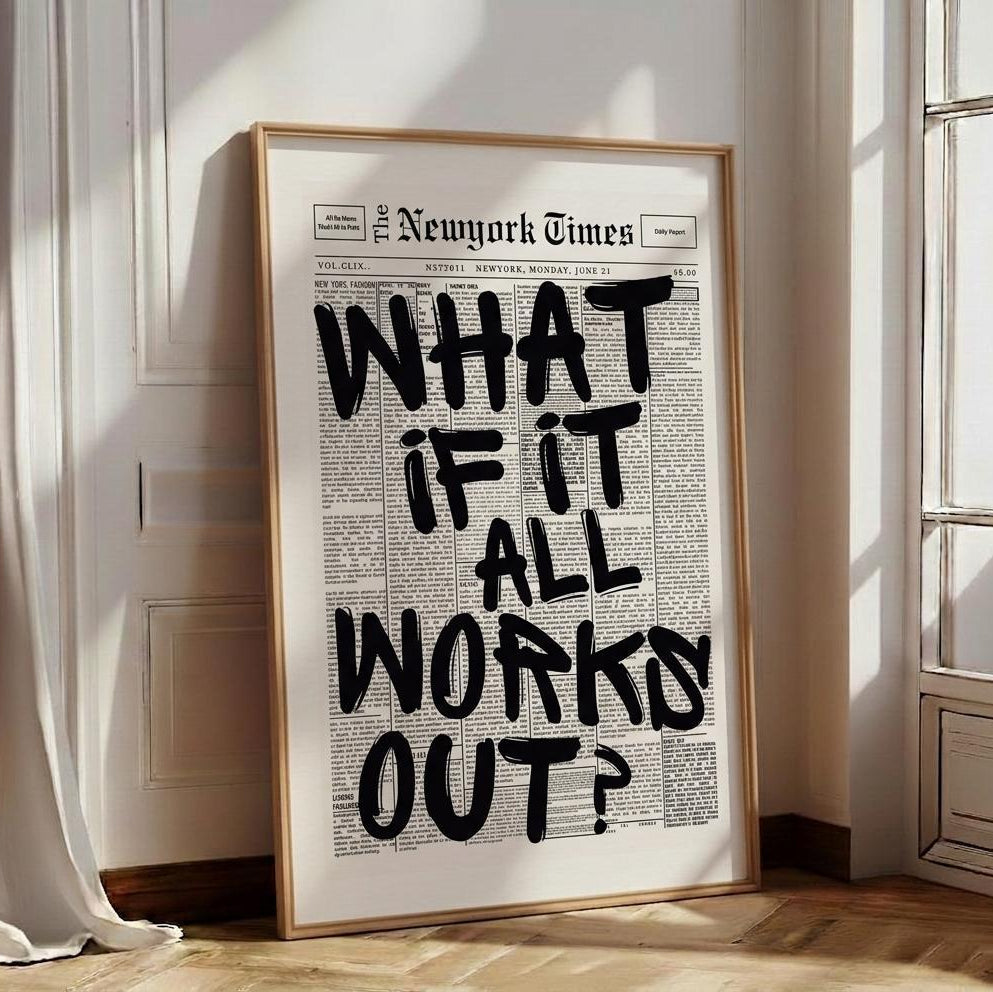 A framed art print featuring a New York Times newspaper design with the text 'WHAT IF IT ALL WORKS OUT?' in large black letters, leaning against a wall on a wooden floor in a sunlit room.