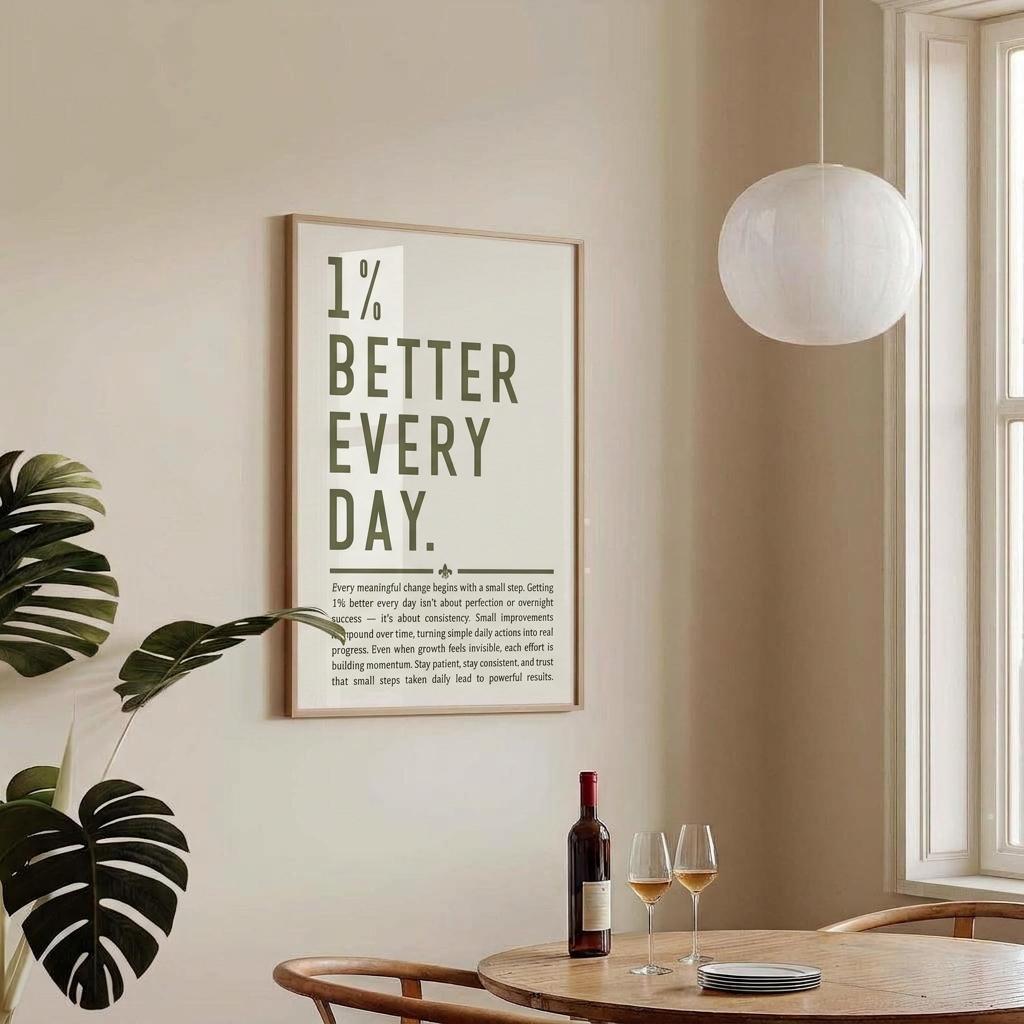 A framed vertical wall art print with the text '1% BETTER EVERY DAY.' hangs on a beige wall in a bright dining area.