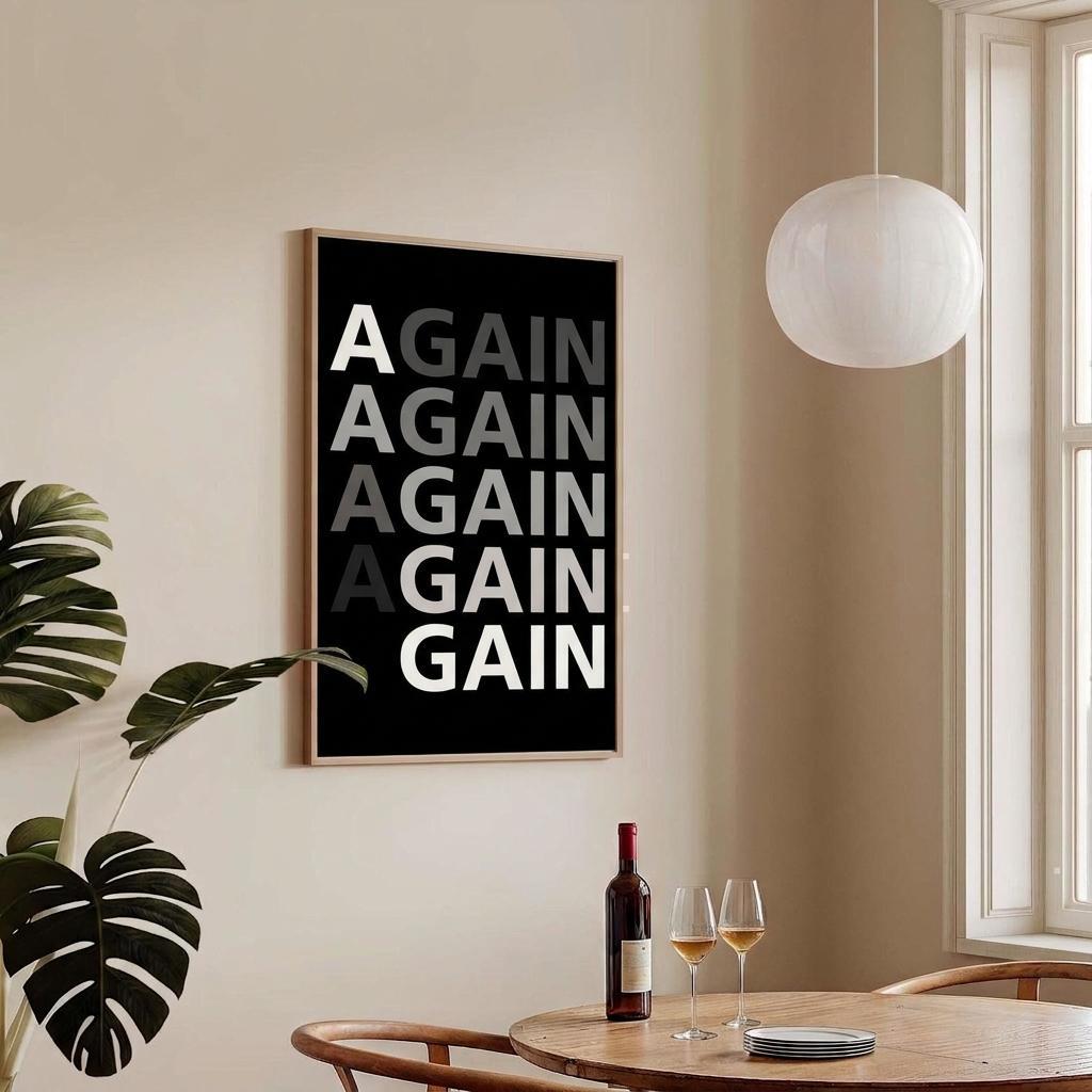 A framed wall art print with the word 'AGAIN' repeated vertically in white, gray, and black text on a black background, hanging on a beige wall in a dining room setting with a table, wine bottle, glasses, and pendant light visible.