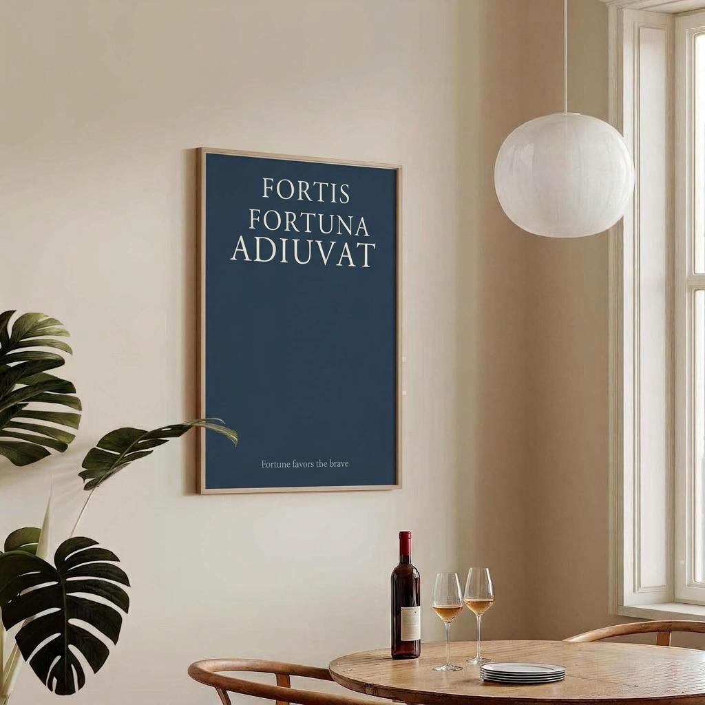 A framed wall art print with the Latin phrase 'FORTIS FORTUNA ADIUVAT' in white text on a dark blue background, displayed in a warm beige room above a wooden dining table with wine glasses and a bottle.