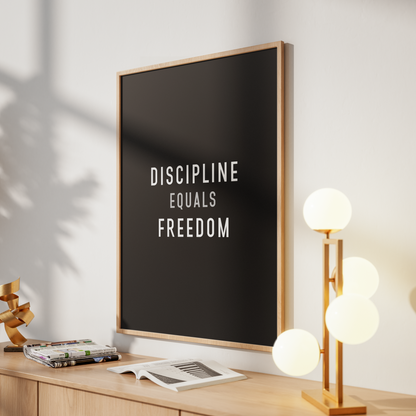 A framed wall art print with the text 'CARPE DIEM*' on a dark background, leaning on a light wood console table in a styled interior with a glowing multi-light lamp and soft shadows.