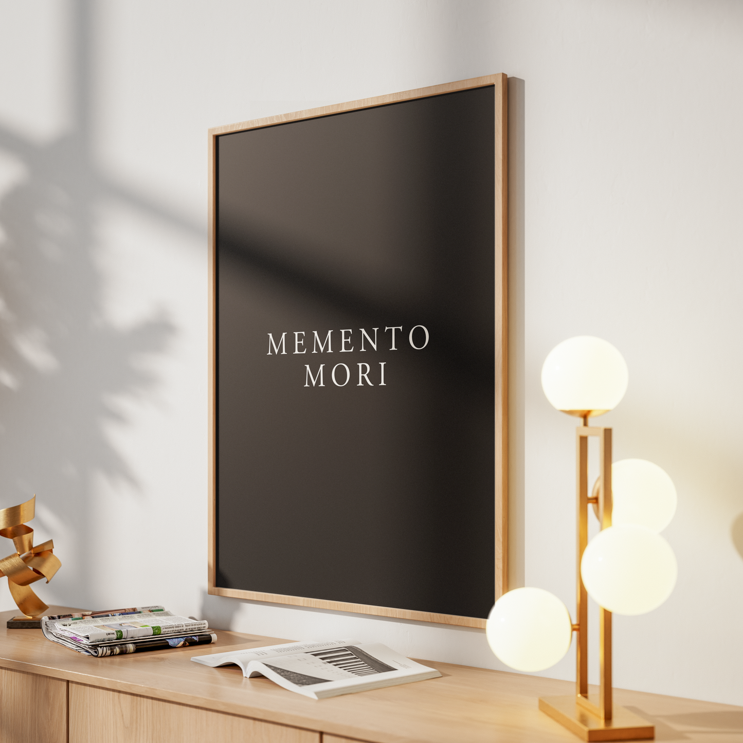 A framed wall art print with the words 'GUARD YOUR HEART' in a faded pink tone on a dark burgundy background, displayed on a light wood console against a white wall with warm sunlight and shadows.