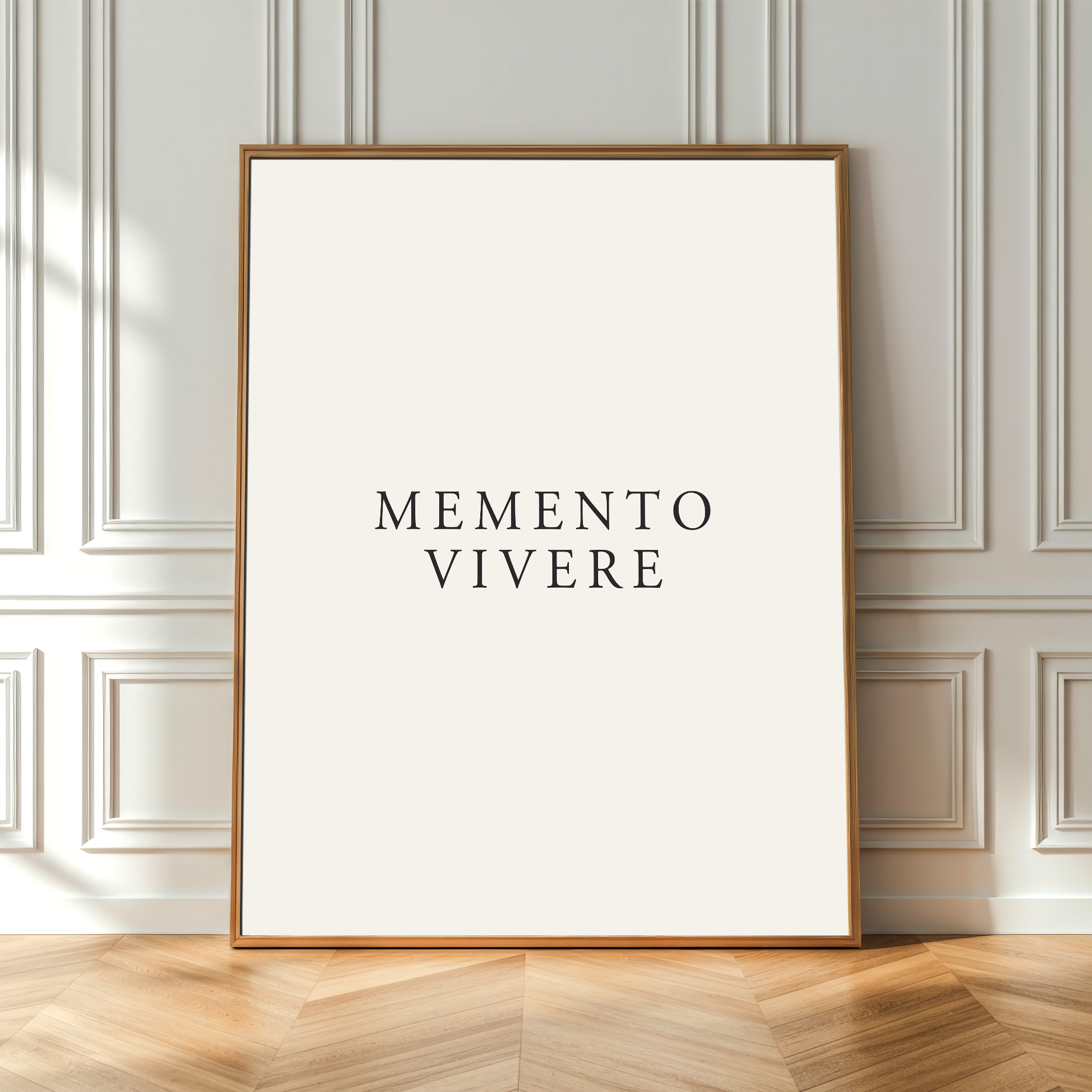 A framed minimalist art print with the text 'MEMENTO VIVERE' in black serif lettering on an off-white background, leaning against a light gray paneled wall on a light wood herringbone floor.