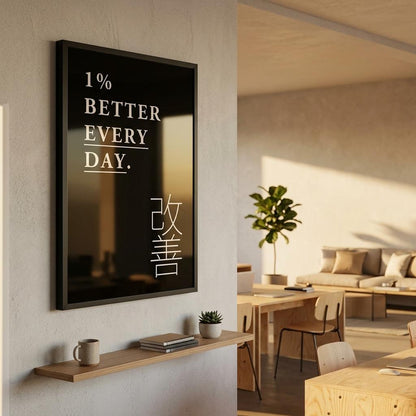 A framed wall art print with the English phrase '1% BETTER EVERY DAY.' and Japanese characters on a black background, displayed in a modern interior room with a shelf, mug, plant, and seating area.