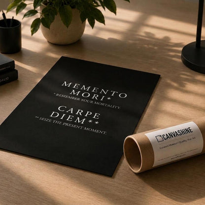 A black poster or print with white text reading 'MEMENTO MORI', 'CARPE DIEM', and 'SEIZE LE PRESSENT MOMENT' lies on a wooden desk beside a rolled kraft paper tube labeled CANVASHINE. The scene is styled with books, a pen, a small plant, and a lamp in warm natural light.