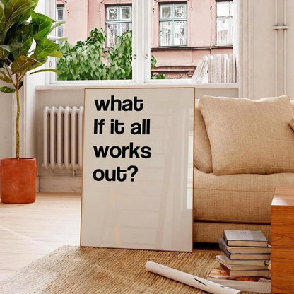 A vertical framed art print with the text 'what If it all works out?' in black sans-serif font on a white background, leaning against a beige sofa in a bright, modern living room.